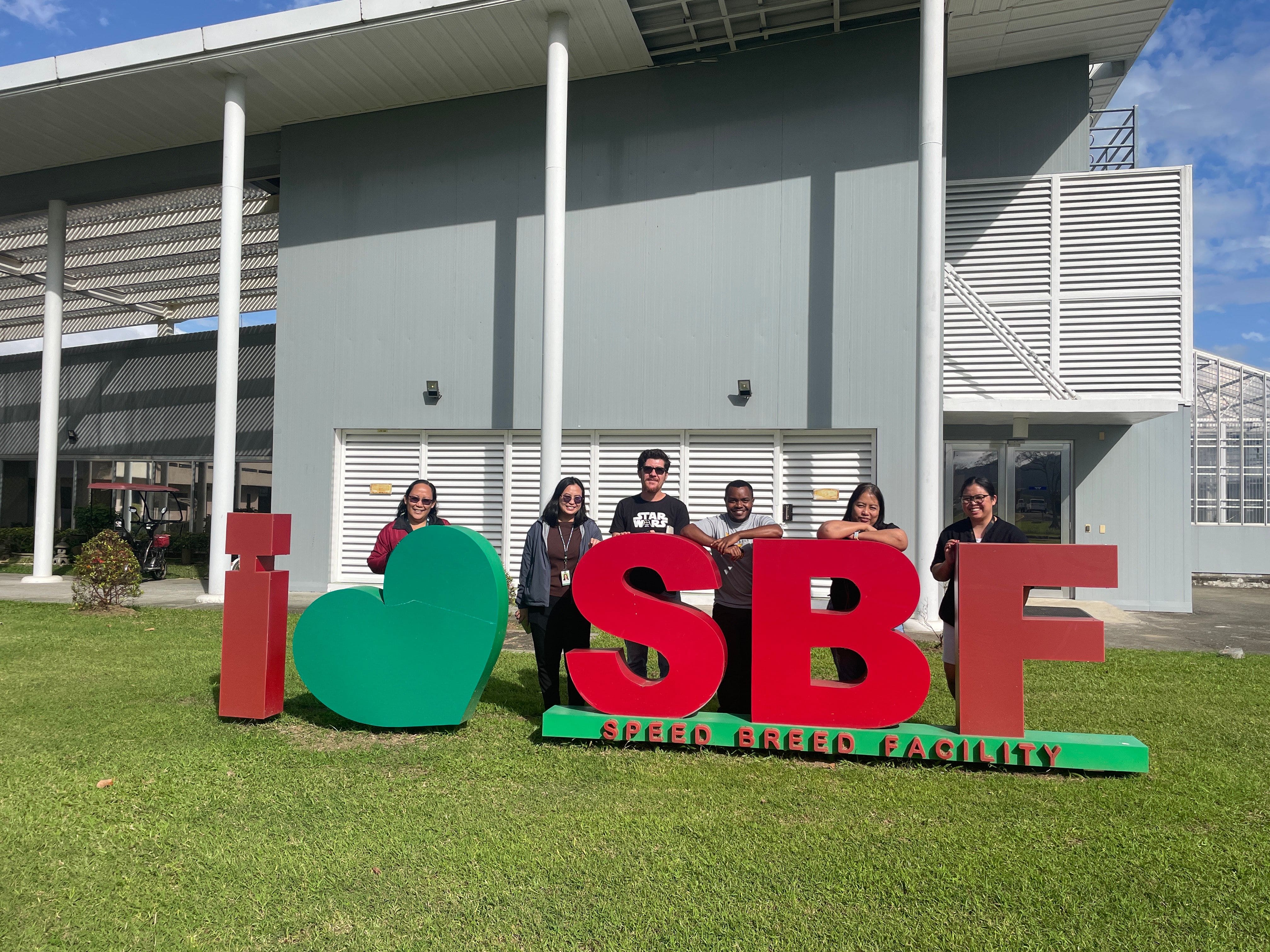 (L-R) Consie Parducho, Steph Manrilla, Luis Hernández, David Muruu, May Sallan, and Rica Mariano pose in front of IRRI HQ’s Speed Breeding Facility